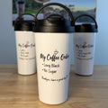 Three white insulated coffee carry mugs with black lids are arranged on a wooden tabletop, with a printed coffee-themed backdrop card behind them. The front mug is largest and centered, with the text 'My Coffee Order' and smaller phrases printed on it.