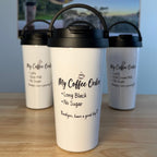 Three white insulated coffee carry mugs with black lids are arranged on a wooden tabletop, with a printed coffee-themed backdrop card behind them. The front mug is largest and centered, with the text 'My Coffee Order' and smaller phrases printed on it.