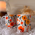 Two floral-patterned mugs on a white surface with a candle and decorative items in the background.