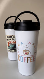 Two white tumblers with black lids, one featuring a coffee-themed design and the other with text.