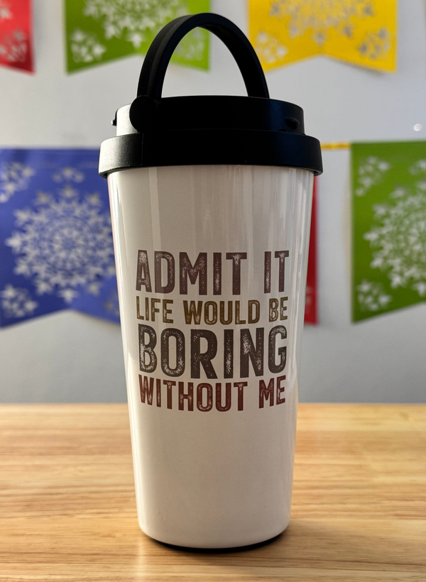 White tumbler with text on a wooden surface with colorful flags in the background