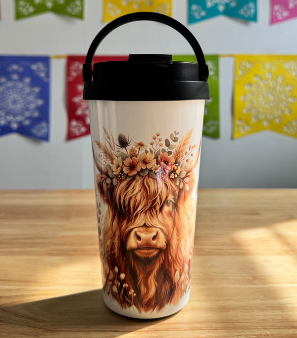 Tumbler with a cow design on a wooden surface with colorful flags in the background